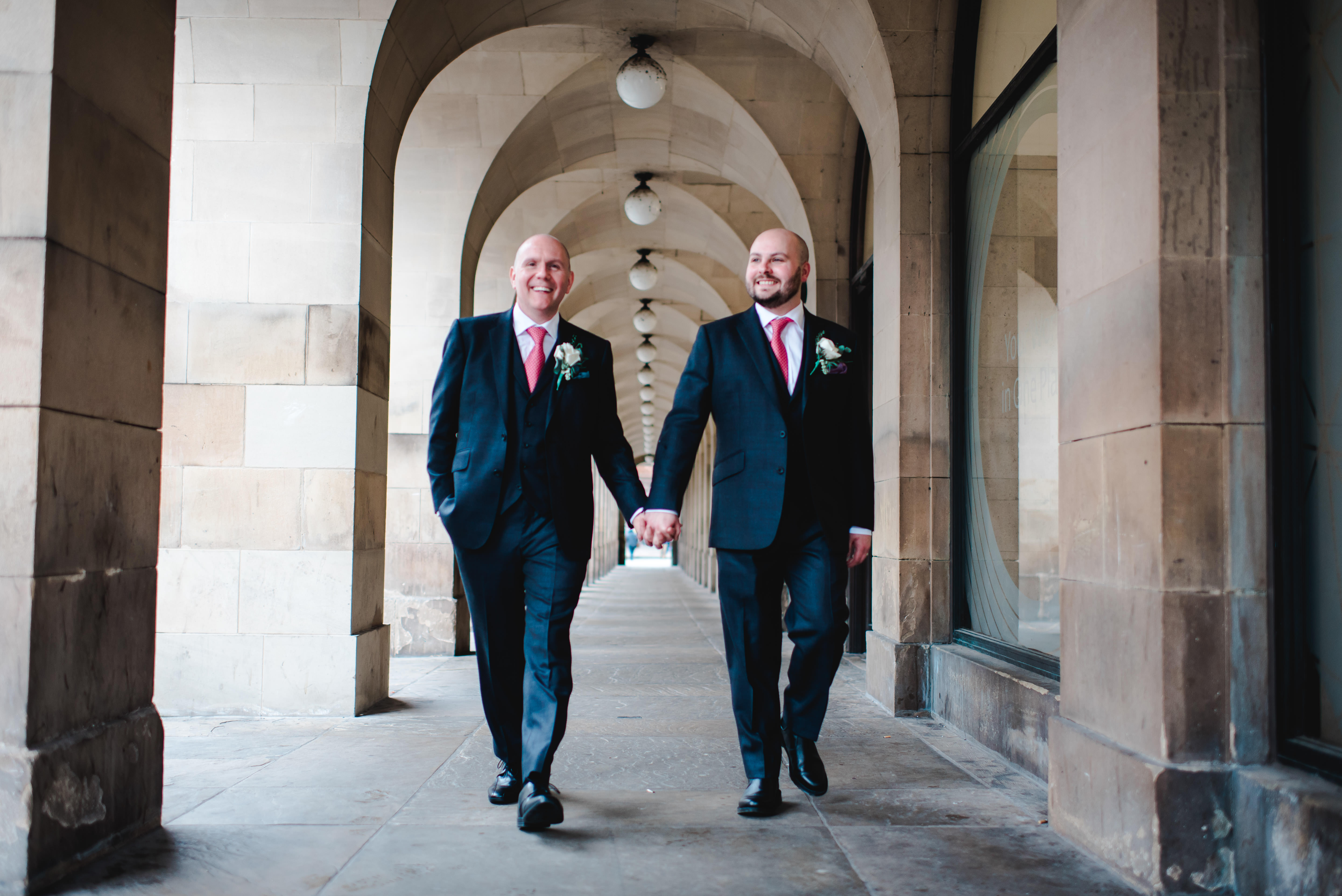Groom and groom walking hand in hand in Manchester Town Centre